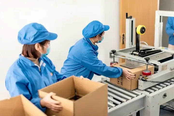 Packing reference showing workers handling cartons at a packing station